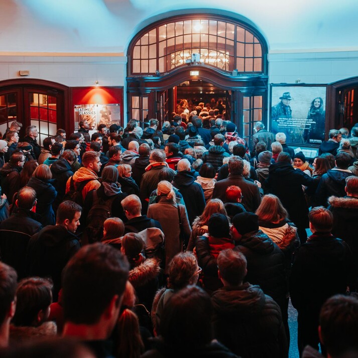 Crowd waiting in a foyer to attend a popular film event.